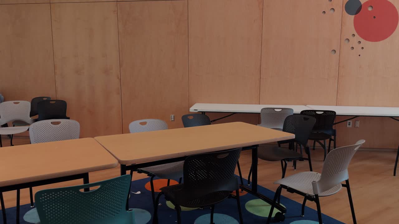 Slow glide pan across empty classroom meeting space with tables and chairs