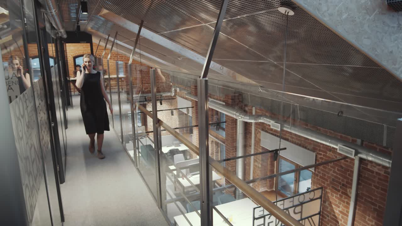 Pretty Businesswoman Chatting in Call Phone while Going through Hallway