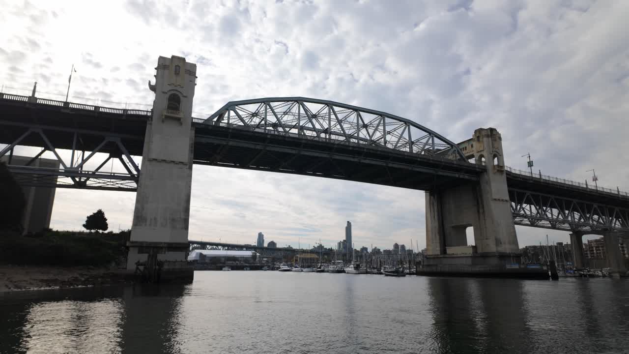 Gimbal wide booming down shot of the Burrard Bridge spanning False Creek on an autumn day in Vancouver, British Columbia, Canada. 4K