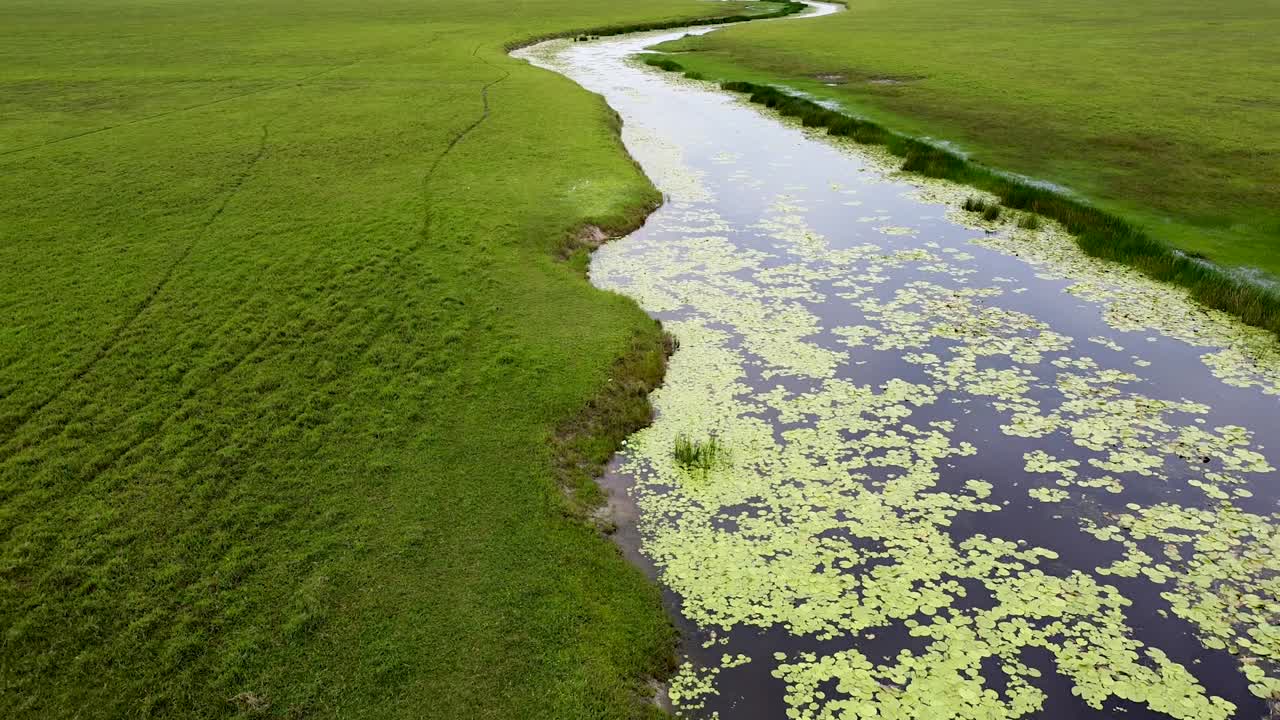 Reversal down stream river surrounded by vast open plain wetlands landscape at Ira Lalaro, Nino Konis Santana National Park, Timor Leste, aerial drone reversing