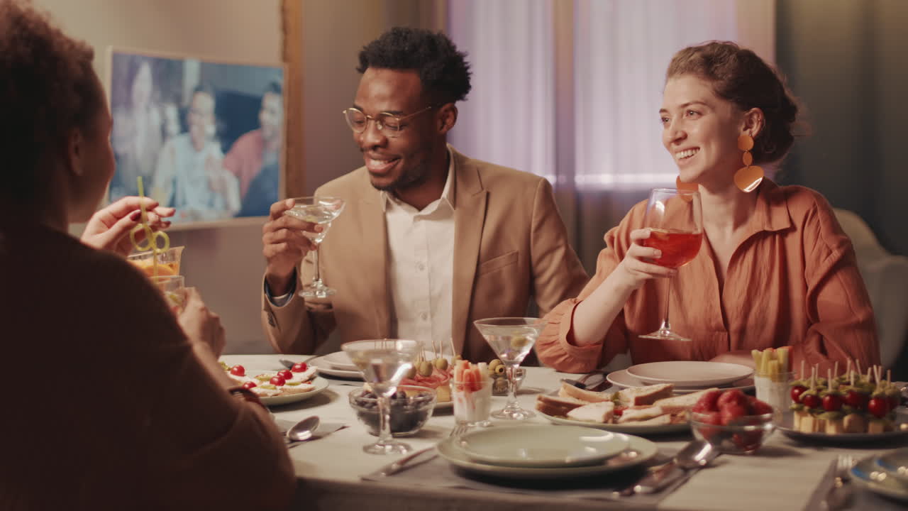 Multiethnic Friends Toasting with Cocktail Drinks at Dinner Party