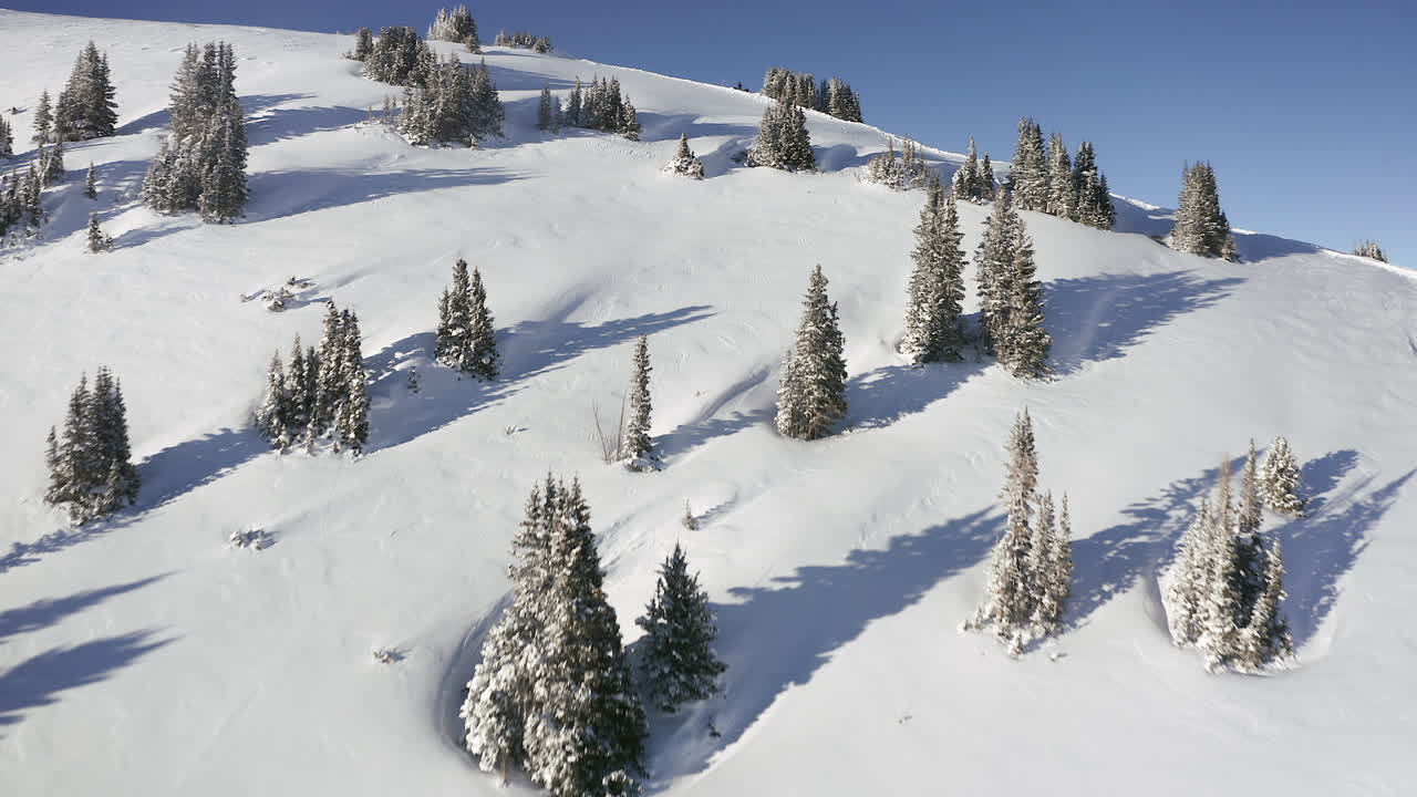 Aerial cinematic flyby over mountain pass peak with snowmobiler at top of Vail Pass Colorado Epic scenery day fresh snow