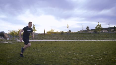 panning shot of a tall athletic man running across a grass field