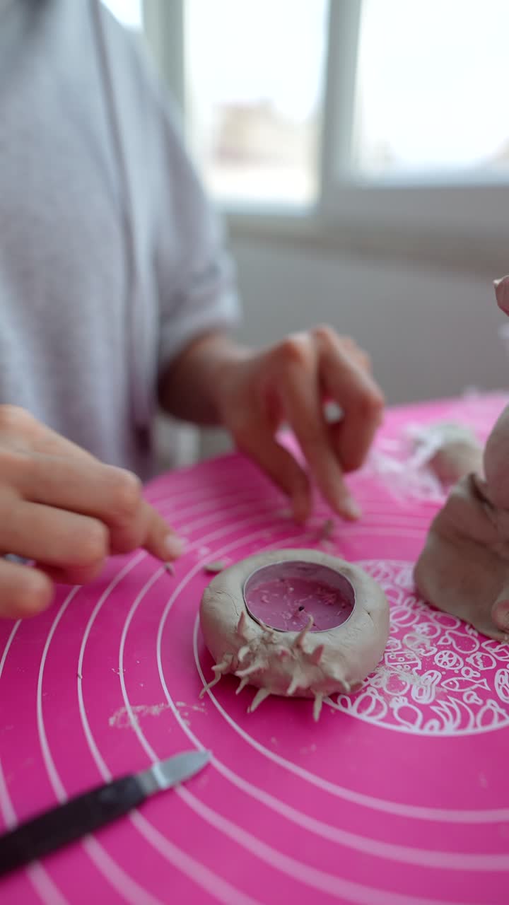 Primo piano di mani che modellano l'argilla su un tappetino rosa