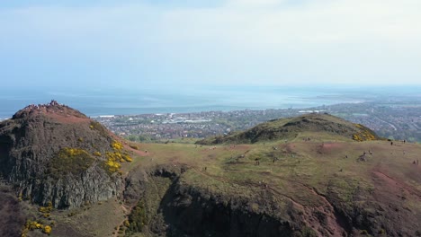 flying over arthur's seat, to reveal the south of edinburgh and tourists walking | edinburgh, scotland | 4k at 30 fps