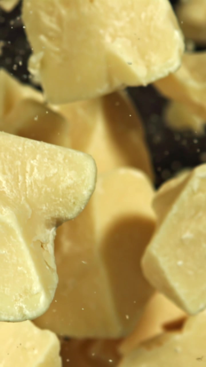 Pezzi di burro di cacao grezzo che cadono al rallentatore