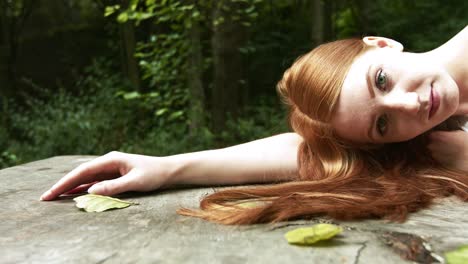 Cute-relaxed-redhead-girl-looking-to-camera-on-sunny-summer-day-at-park