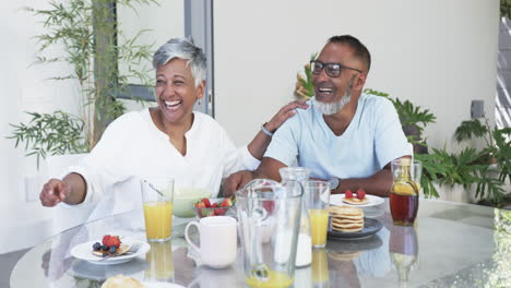 biracial couple enjoys a hearty breakfast, sharing a laugh together