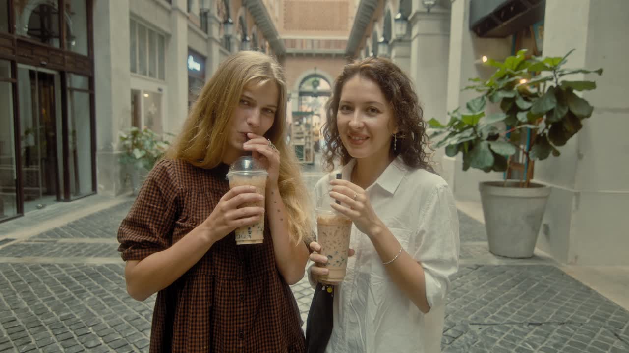 Two Friends Enjoying Bubble Tea in a Shopping Arcade
