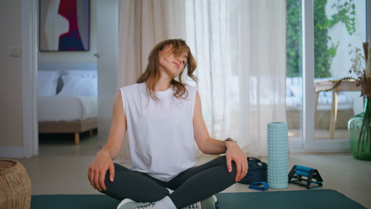 Fit girl warming neck on yoga mat turning on sport tutorial video. Young woman