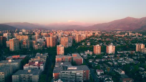 Vista-Aérea-De-Dolly-En-La-Zona-Residencial-De-Las-Condes-Con-La-Cordillera-De-Los-Andes-Al-Fondo-Al-Atardecer,-Santiago,-Chile