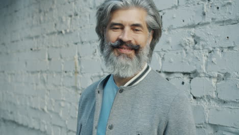 smiling older man in front of a brick wall
