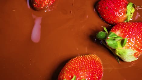 strawberries being dipped into melted chocolate