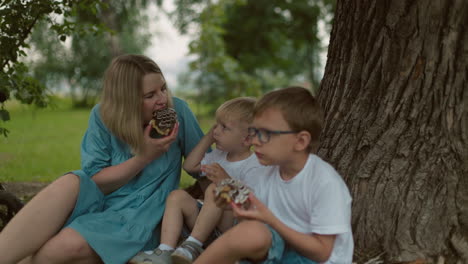 a mother enjoys her snack alongside her older child, while the younger one gazes at her in curiosity