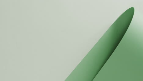 Close-up-of-green-rolled-piece-of-paper-on-white-background-with-copy-space-in-slow-motion