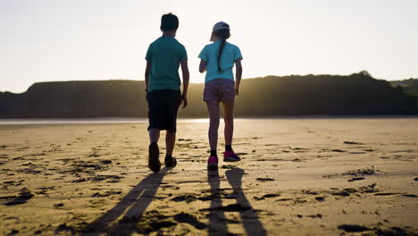 niños caminando por la playa al atardecer