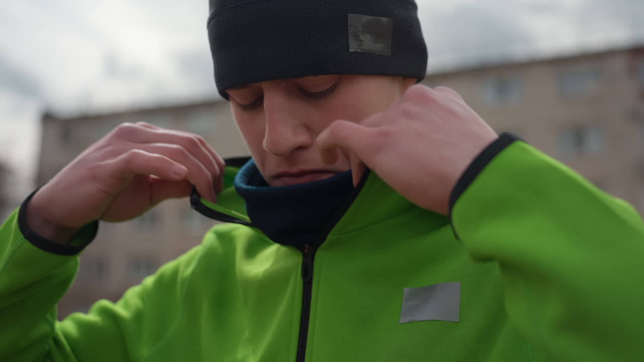 Un hombre se prepara para una actividad deportiva; un hombre caucásico se ajusta la ropa antes de un evento o práctica deportiva; un hombre con ropa deportiva informal se prepara mental y físicamente para un próximo partido o sesión.
