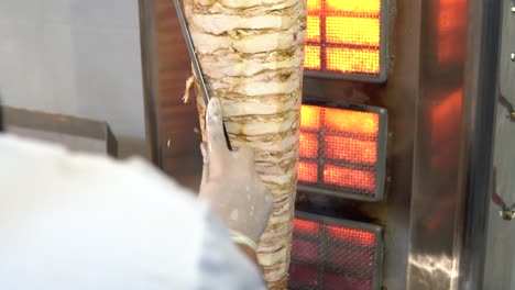 Chef-Skillfully-Carving-Grilled-Chicken-Meat-Shawarma-from-Rotisserie,-Close-Up