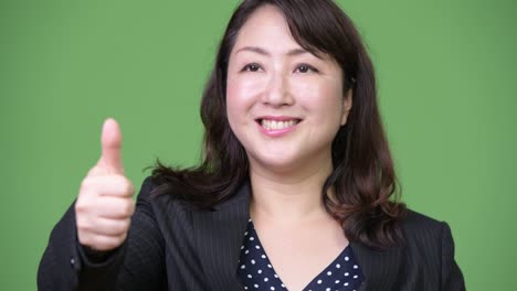 성숙하고 아름다운 아시아 사업가 여성이 엄지손가락을 올리고 있습니다.