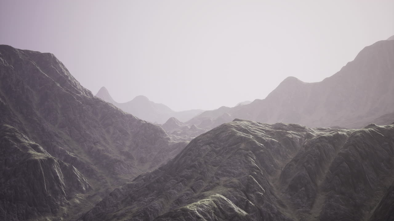 Majestic mountain range under a soft hazy sky at dawn hour