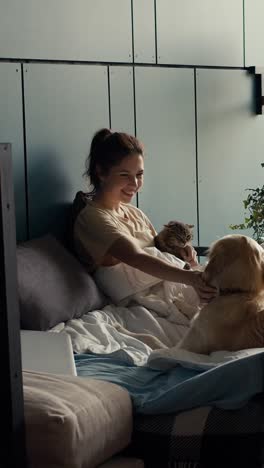 woman relaxing with cat and dog on bed