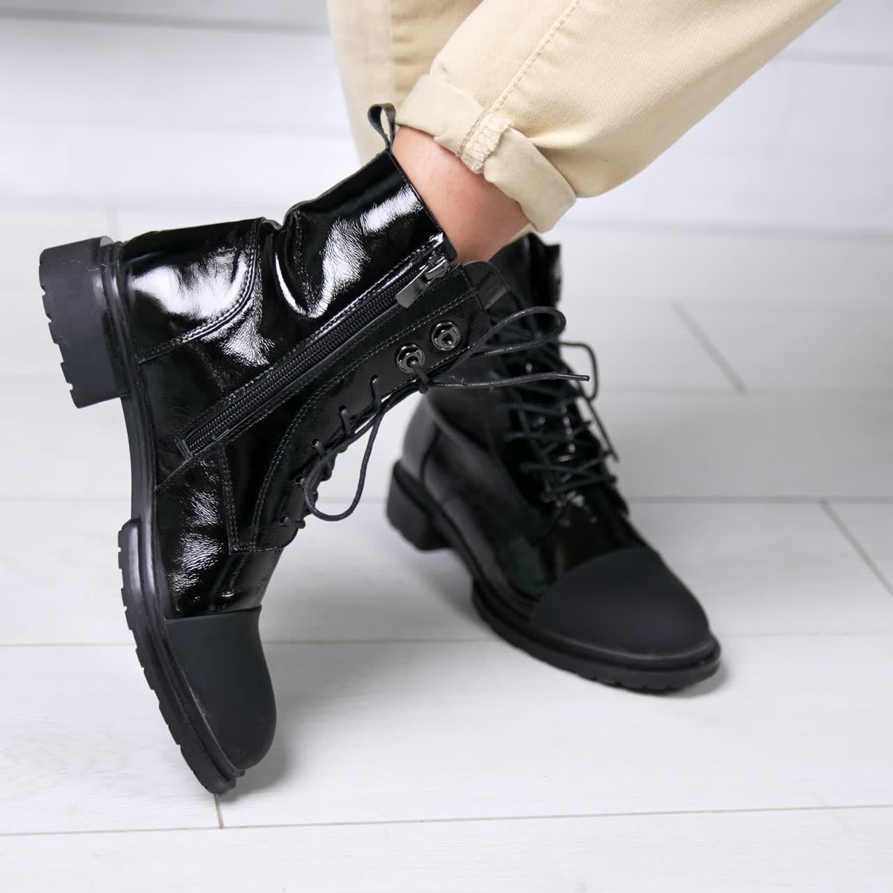 Female wearing black lacquered boots with opaque nosepieces. Model stands and turns around in her comfortable stylish footwear. Close up