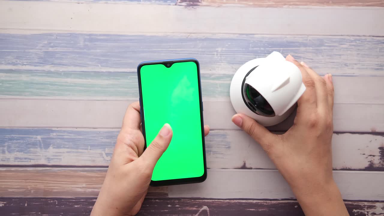 teléfono inteligente y cámara de seguridad en una mesa de madera