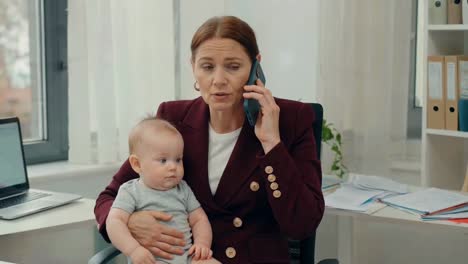 mother on phone with baby in office setting