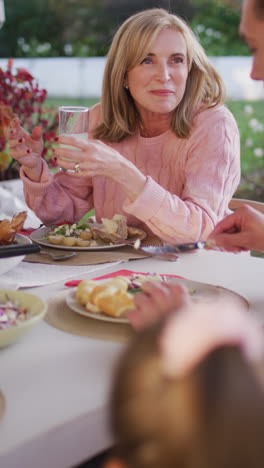 video vertical de una madre caucásica senior feliz hablando con su hijo adulto en la mesa de la cena familiar