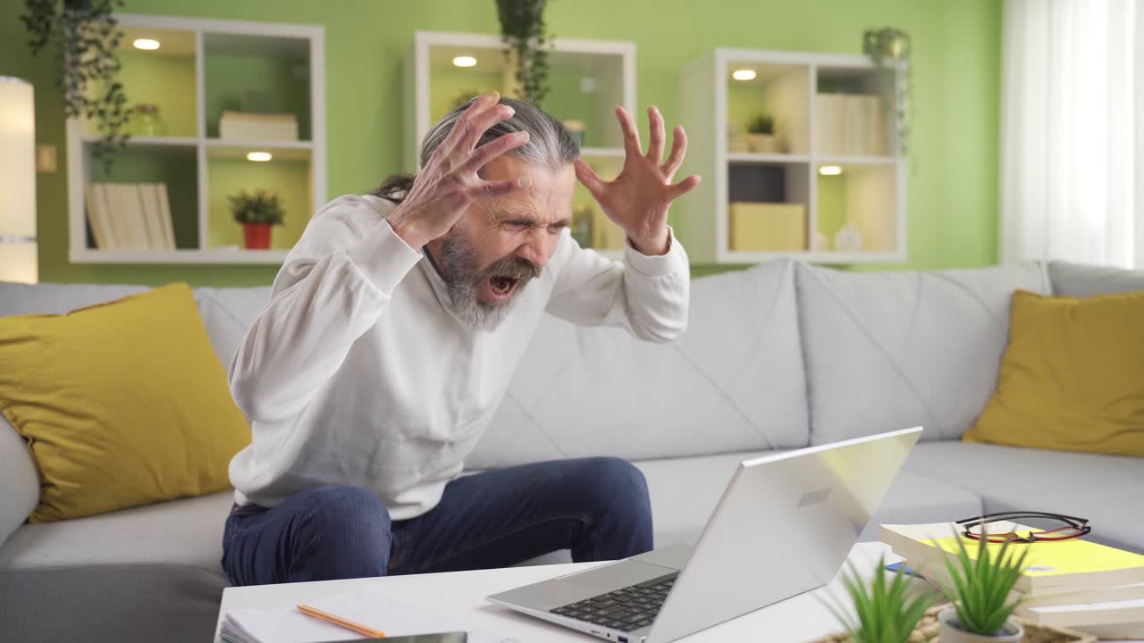 el hombre serio enfocado en la computadora portátil en casa se está enojando.