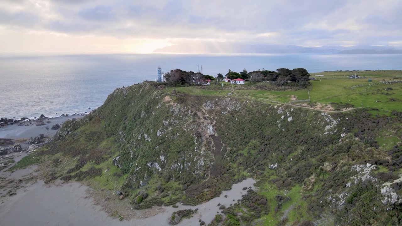 Ripresa aerea drammatica con gru del Faro di Baring Head sotto cieli tempestosi, Wellington, Nuova Zelanda