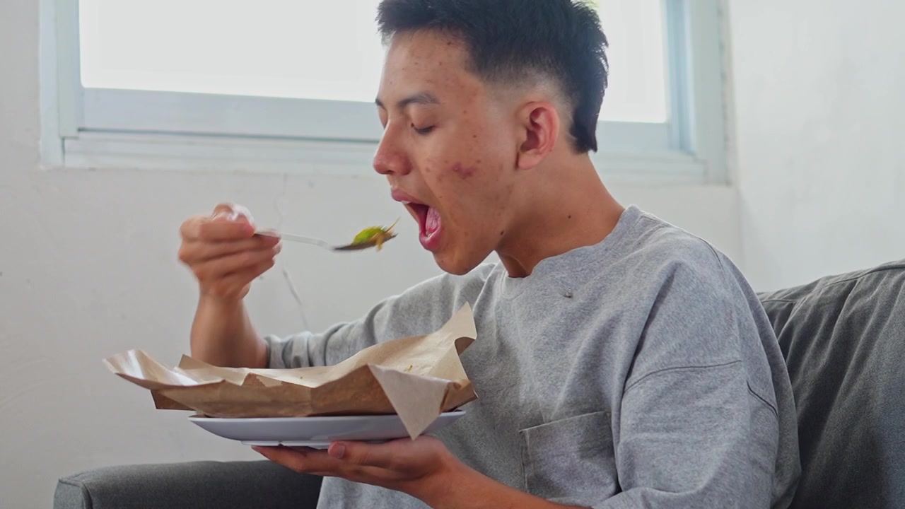 Side view of man eating karedok or traditional indonesian salad served on paper