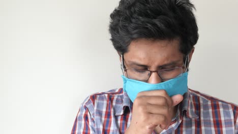 man coughing while wearing a mask