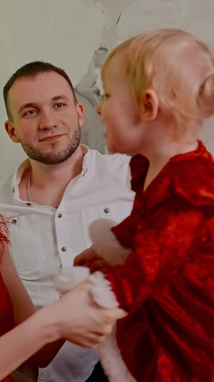 A Heartwarming Holiday Moment Captured: A Charming Interaction Between a Father and His Daughter Dressed in Festive Red, Radiating Joy and Love During the Christmas Season in Their Cozy Home