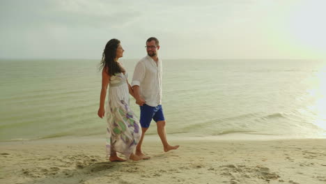 Joven-Pareja-De-Enamorados-En-Ropa-Ligera-Sin-Preocupaciones-Corriendo-En-Una-Playa-Tropical-Limpia