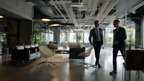two businessmen walking and talking in a modern office lobby