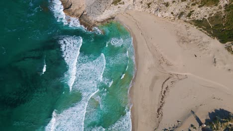 Bird-view-beach-bay-with-clear-turquoise-sea-water,-green-hills,-white-sand