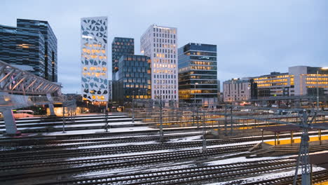 train leaving oslo central station with barcode project buildings at night in bjorvika, oslo, norway