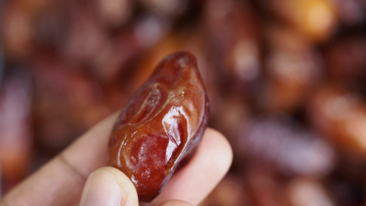 Close-Up of Hand Holding a Single Date Fruit