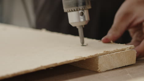 man screwing with a drill a piece of wood