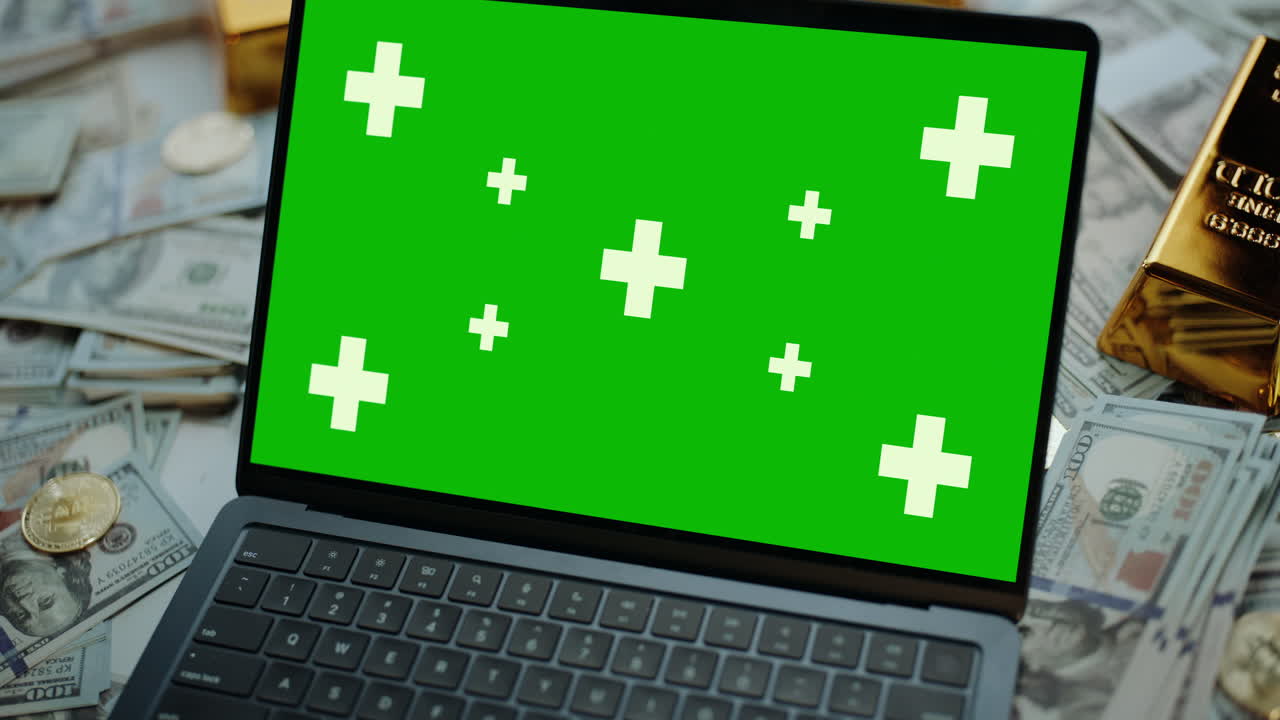 Laptop with Green Screen Surrounded by Money and Gold