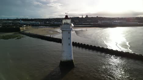 New-Brighton-Perch-Rock-Lighthouse,-River-Mersey,-Wirral---aerial-drone-close-clockwise-pan,-New-Brighton-waterfront-reveal-on-a-sunny-winter-afternoon-08
