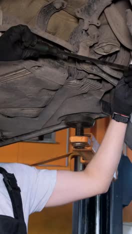 auto mechanic working on car undercarriage in a workshop