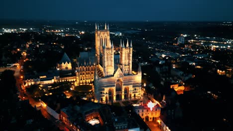 aerial drone video captures the renowned lincoln cathedral in lincolnshire, uk, at dusk, showcasing its majestic gothic architecture with illumination