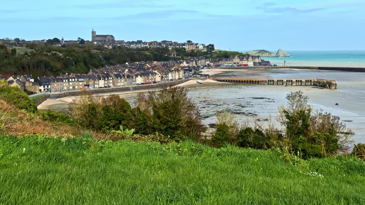 Une ville côtière avec des rangées de maisons et une église lointaine surplombe un large littoral et une mer calme. Convient aux documentaires de voyage et aux promotions immobilières.