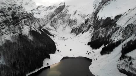 aerial flyover over lake seealpsee in appenzell, switzerland with a winter landscape full of snow and views of cliffs and peaks of alpstein