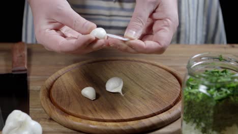 Peeling-garlic-on-round-wooden-board,-for-preparation-of-argentine-chimichurri