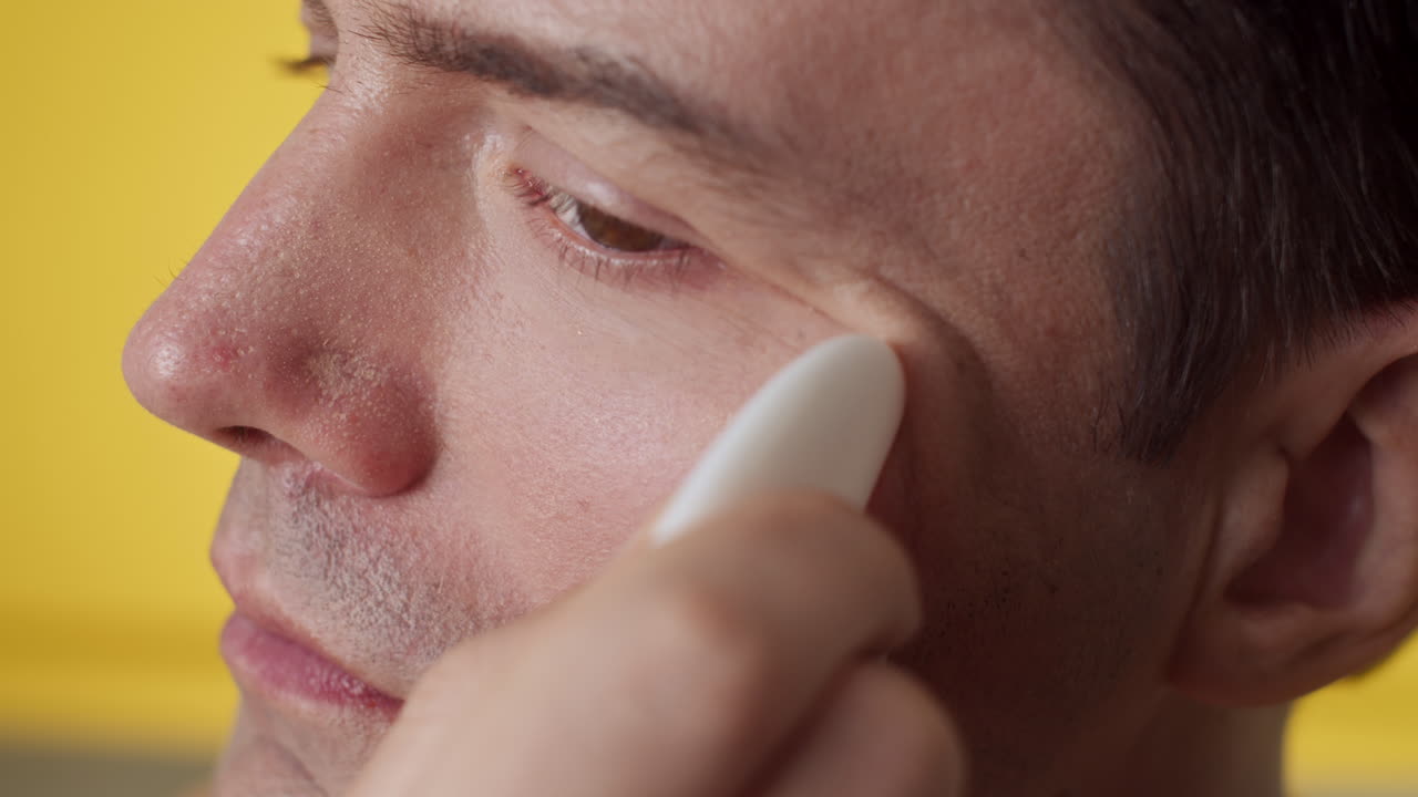 Man Smoothing Wrinkles under Eyes with Gua Sha Tool