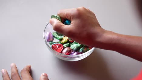 person eating colorful chocolate candies from a bowl