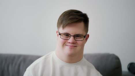 Kind-young-man-with-down-syndrome-sitting-on-the-sofa